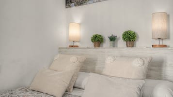 Un dormitorio con cabecera de madera, dos lámparas de noche y tres plantas en macetas.