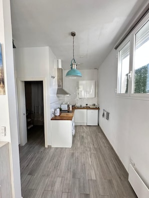 A modern kitchen with white cabinets, a wooden countertop, a built-in oven, and a hanging light fixture. - Apartment 'Calma' with Wi-Fi (Tarifa)