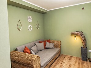 A cozy room with a grey sofa, wicker ottoman, and a wall-mounted light fixture. - Le fonti by Interhome (Foiano della Chiana)