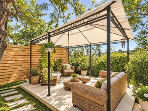 An outdoor patio area with a covered seating area, wicker furniture, and potted plants. - Le fonti by Interhome (Foiano della Chiana)