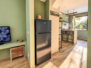 A modern kitchen with a black refrigerator, a wooden bench, and a 'Welcome' sign. - Le fonti by Interhome (Foiano della Chiana)