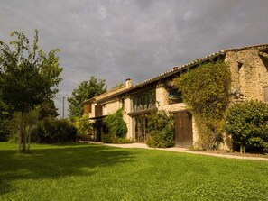 A stone building with a sloped roof, surrounded by a well-maintained lawn and trees. - Charming Holiday Home With Pool - 904 ANS (Ansouis)
