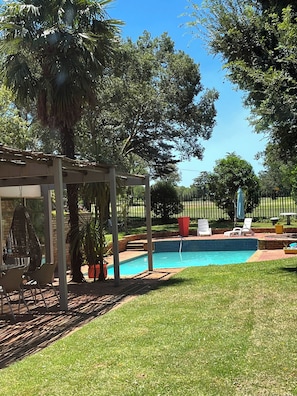 Quintal com piscina, espreguiçadeiras e pérgola.