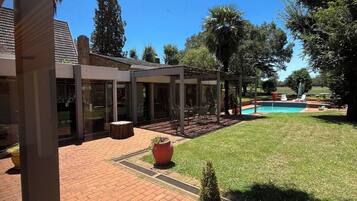 A courtyard with a swimming pool, a brick patio, and a building with large windows.