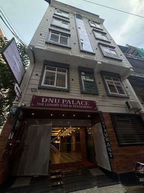 A multi-story building with a sign for 'DNU PALACE THE LUXURY STAY & RESTAURANT' on the ground floor. - Hotel DNU Palace (Varanasi)