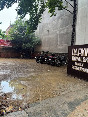 A parking area with motorcycles and a sign for 'Darkin Royal Sk Family Restaurant.' - Hotel DNU Palace (Varanasi)