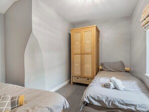 A bedroom with two beds, a wooden wardrobe, and a window. - 3 bedroom accommodation in Buxton (Buxton)