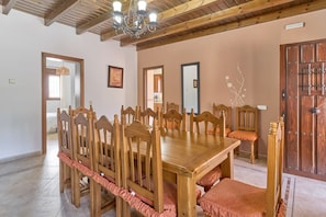 A dining room with a wooden table and chairs, a chandelier, and a wooden door. - Villa Alejandro in Sayalonga. Located on a quiet, sunny private estate (Sayalonga)