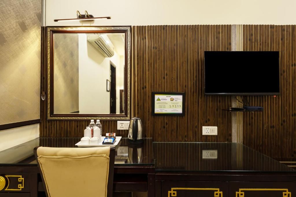 Een hotelkamer met een grote spiegel, een flatscreen televisie, een houten paneelwand, een klein tafeltje met toiletartikelen en een lederen fauteuil.