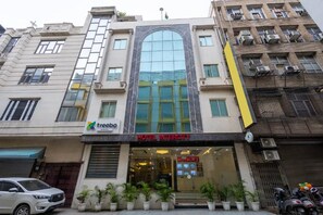 Un hotel con fachada moderna, un amplio acceso de vidrio y un cartel que indica que es un hotel.