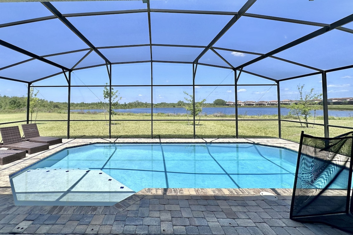 A covered outdoor swimming pool with lounge chairs and a view of a lake.