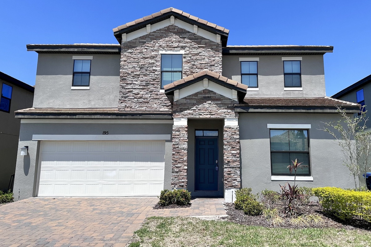 A two-story house with a stone facade, a garage, and a front door.