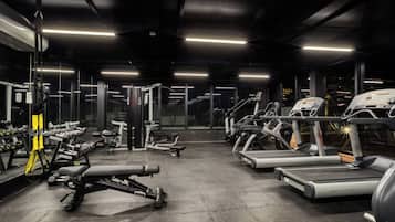 Un gimnasio con cintas de correr, mancuernas y máquinas de pesas.