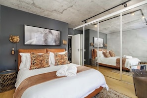 Ein modernes Schlafzimmer mit einem großen Bett, einem Spiegel und einem gerahmten Bild an der Wand.