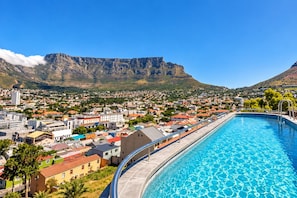 Ein Schwimmbecken mit Blick auf eine Stadt und Berge im Hintergrund.