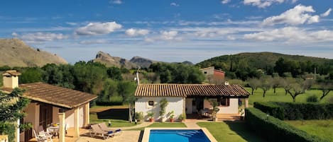 Una villa con piscina, mobiliario exterior y vistas a las montañas.