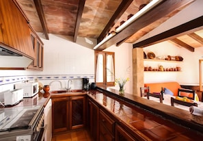 A kitchen with wooden cabinets, a stove, and a coffee maker. - Villa 'Juanito' with Private Pool, Wi-Fi and Air Conditioning (Illes Balears)
