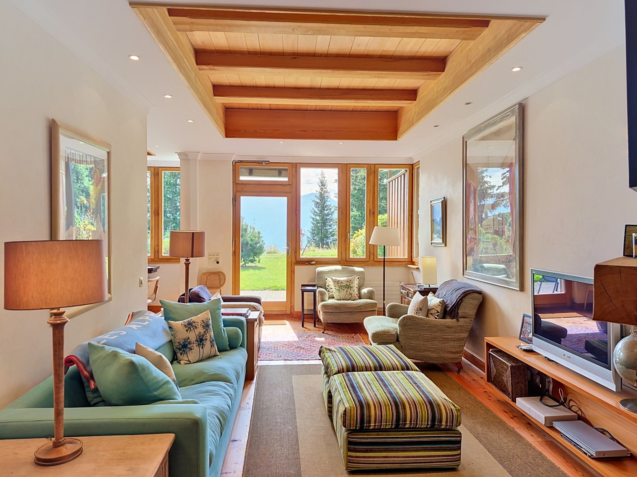 A spacious living room with a large window, a television, and a sofa.