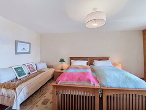 A bedroom with a bed, a sofa, a nightstand, a lamp, and a framed picture on the wall. - Le Chamois d'Or Combi by Interhome (Crans-Montana)