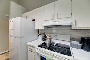 A kitchen with white cabinets, a white refrigerator, a stove, and a kettle. - Havelock Stay Near MCAS Cherry Point & Coast (Havelock)