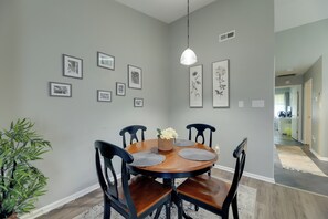 A dining area with a round table, black chairs, and a hanging light fixture. - Havelock Stay Near MCAS Cherry Point & Coast (Havelock)