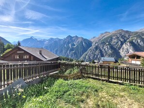 A wooden fence with a view of mountains and a building with a sloped roof. - Apartment Eliane by Interhome (Grächen)