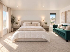 Ein modernes Schlafzimmer mit einem großen Bett, Nachttischen, einem grünen Sofa und Blick ins Freie.