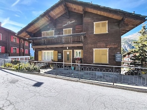 A two-story wooden building with a balcony, a sign reading 'Chalet Eliane,' and a mountain view in the background. - Apartment Eliane by Interhome (Grächen)