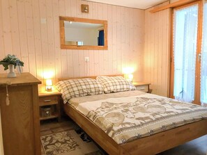 Ein Schlafzimmer mit Holzwandverkleidung, einem Bett, zwei Nachttischen, einem Spiegel und einem Fenster mit Vorhängen.