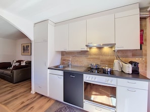 A compact kitchen with white cabinets, a built-in oven, a dishwasher, and a stove. - Apartment Eliane by Interhome (Grächen)