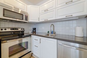 A modern kitchen with white cabinetry, stainless steel appliances, and a tiled backsplash. - Beachfront Extended Escape w/ Workspace! (Santa Monica)