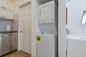 A laundry room with a front-loading washer and dryer, a countertop, and a door with a handle. - Beachfront Extended Escape w/ Workspace! (Santa Monica)