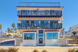 A multi-story building with balconies, large windows, and a sign indicating it is a luxury beachfront apartment complex. - Beachfront Extended Escape w/ Workspace! (Santa Monica)