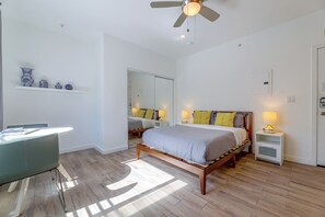 A bedroom with a bed, bedside tables, a desk, and a ceiling fan. - Beachfront Extended Escape w/ Workspace! (Santa Monica)