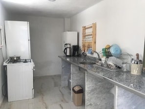 A compact kitchen with a gas stove, a white refrigerator, and a marble countertop. - HINAR HOME (Mardin)