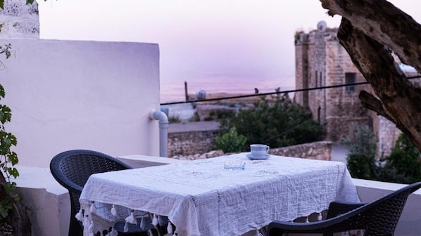 A table with a white tablecloth and two chairs, overlooking a historic building and a sunset. - HINAR HOME (Mardin)