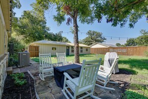 A patio with outdoor seating, a covered table, and a grill. - Adorable 1930s Cottage: Downtown + Dog Friendly (Granbury)
