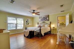 Ein Schlafzimmer mit einem Bett, einem Schminktisch, einem Sessel, einem Deckenventilator und einem Fenster.