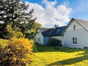 A two-story house with a sloped roof, a visible chimney, and a well-maintained lawn. - Drum Lang Lodge - UK51054 (Isle of Mull)