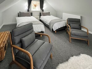Une chambre avec deux lits, une chaise, une petite table et un radiateur.