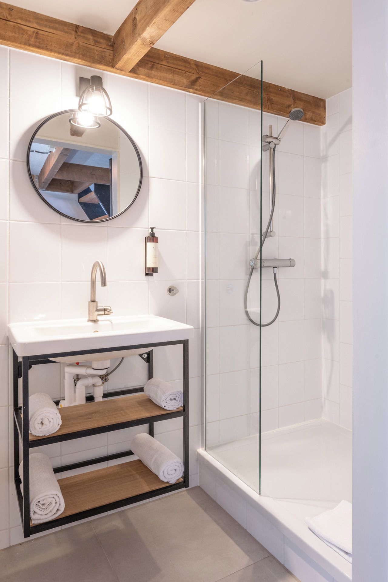 A modern bathroom with a white sink, mirror, and glass-enclosed shower.