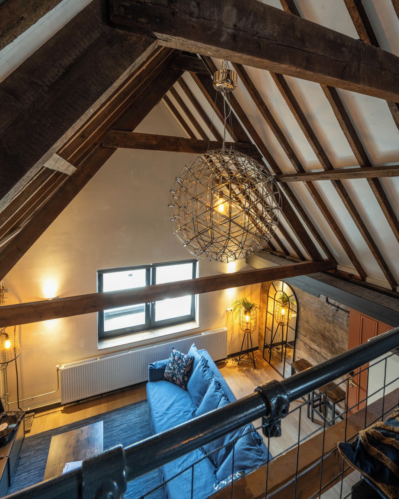 Ein Loft-Zimmer mit freiliegenden Holzbalken, einer Hängelampe, einer Couch und einer Heizung.