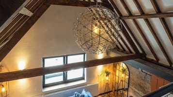 Ein Loft-Zimmer mit freiliegenden Holzbalken, einer Hängelampe, einer Couch und einer Heizung.