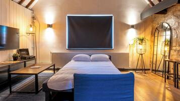 Et moderne hotelværelse med en stor seng, et skrivebord med computer, et fladskærms-TV og en potteplante.