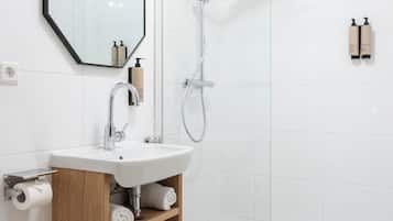 Un bagno moderno con WC, lavandino, doccia e cabina doccia in vetro.