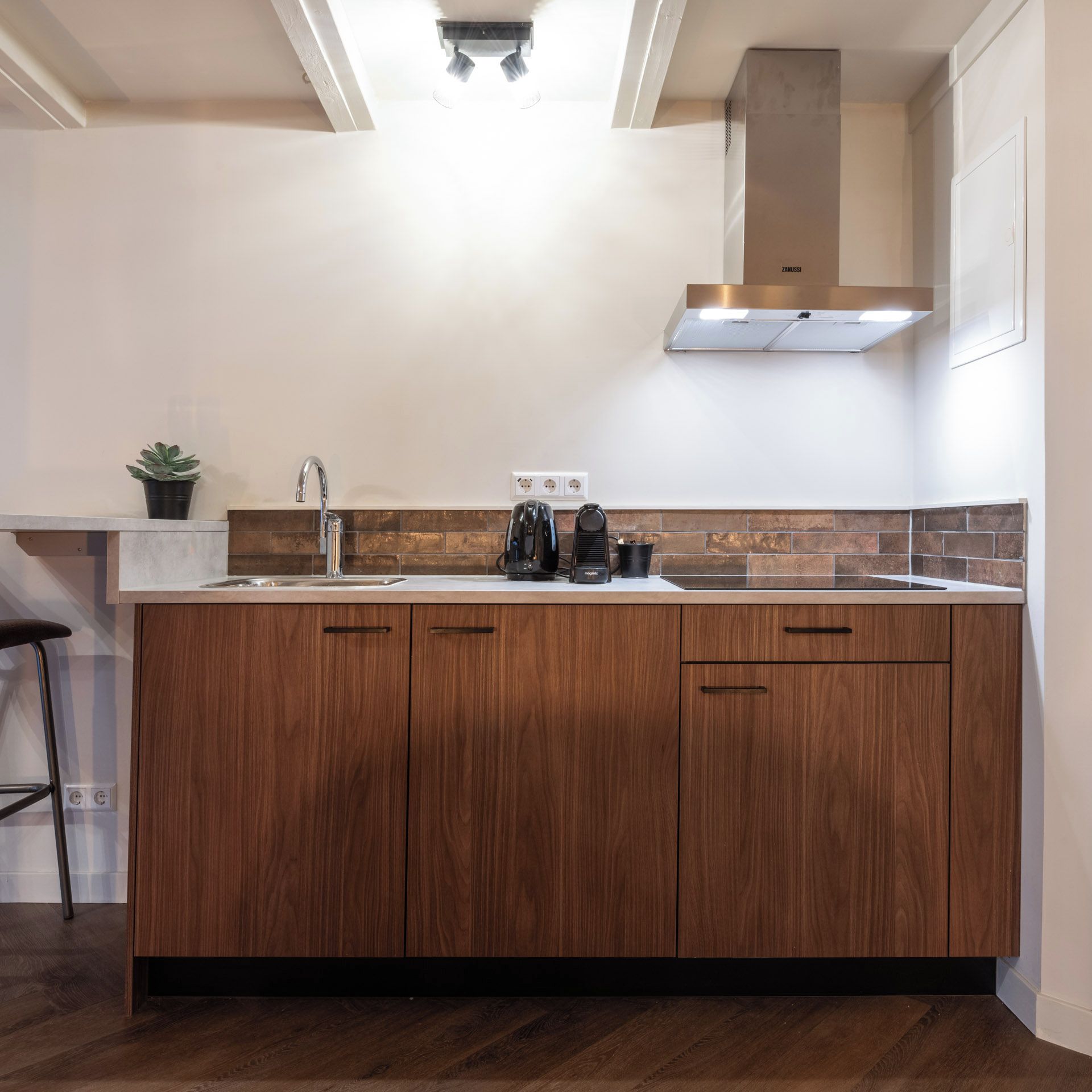 Een keuken met een houten keukeneiland, roestvrijstalen apparatuur en een betegelde achterwand.