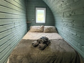 A small, cozy room with a sloped ceiling, a bed with a patterned bedspread, and a window with a view of greenery. - 1 bedroom accommodation in Lerags (Lerags)