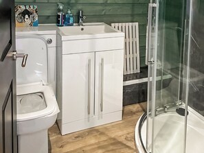 A bathroom with a toilet, a sink, and a shower area. - 1 bedroom accommodation in Lerags (Lerags)