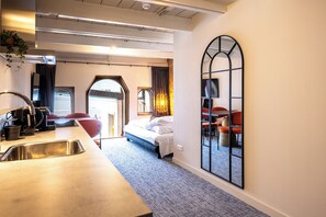 Habitació d'hotel amb llit, escriptori amb rentapistols, cadira i mirall gran.