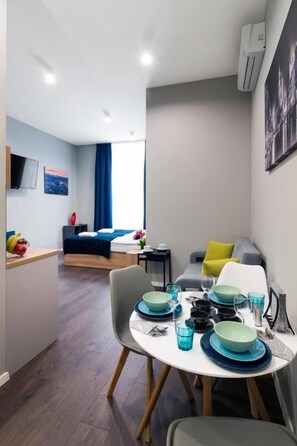 A modern hotel room with a dining area, a bed, and a view of the city. - Kings City Sławkowska Apartments (Kraków)